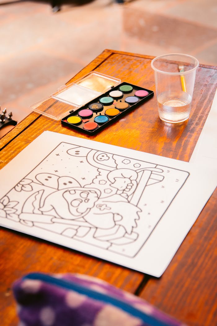 Art supplies setup with watercolors and a coloring page on a wooden table, perfect for creative sessions.