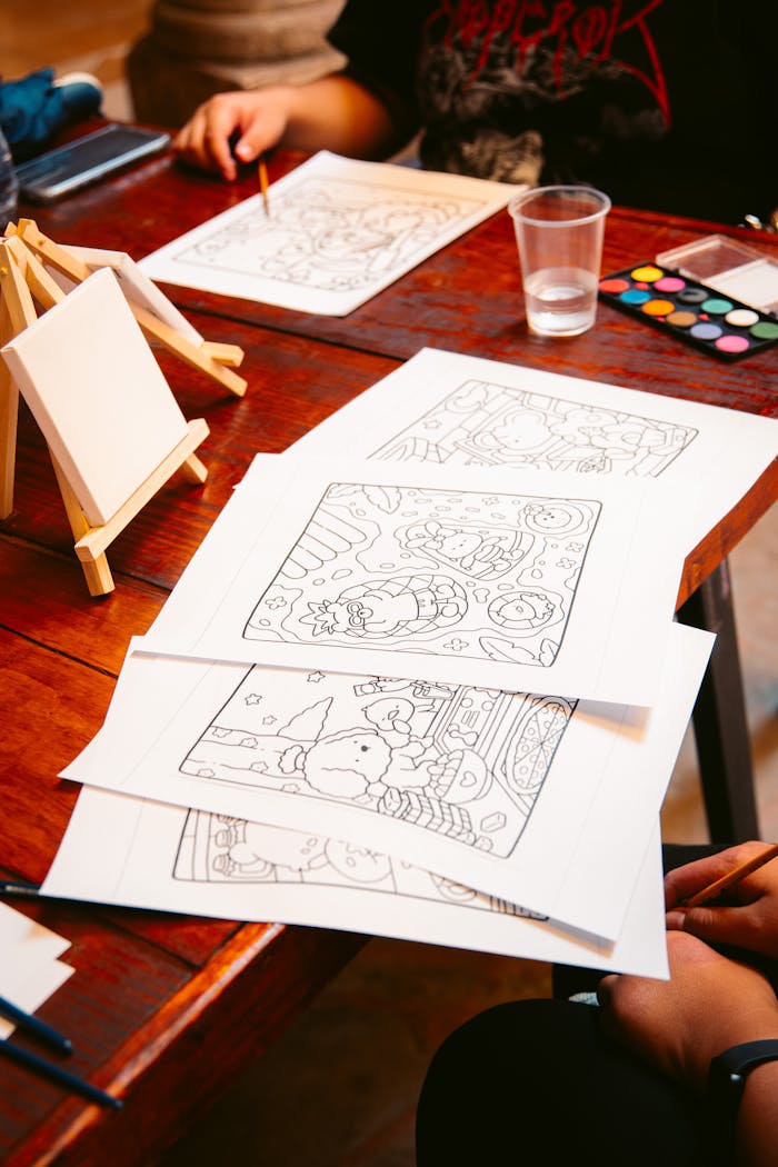 A creative setup for a watercolor coloring activity featuring outlines, paints, and canvases at a table.