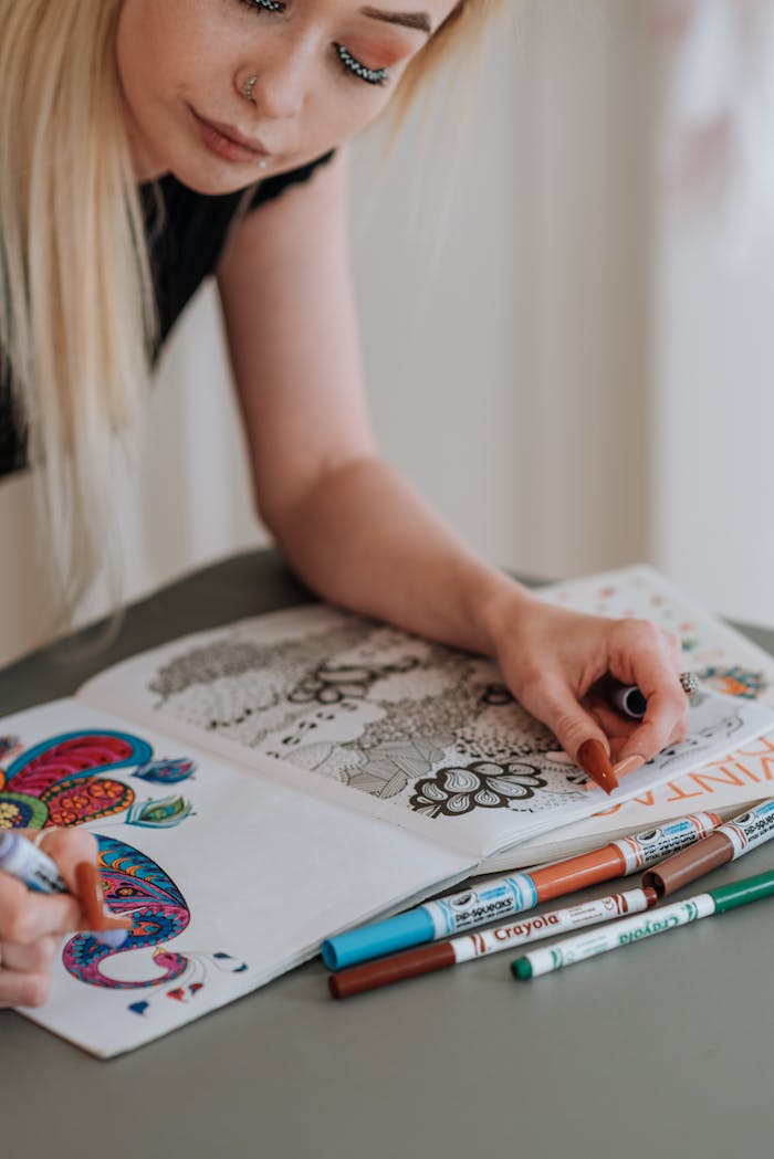 Blonde woman coloring an intricate design using multiple colored pens indoors.
